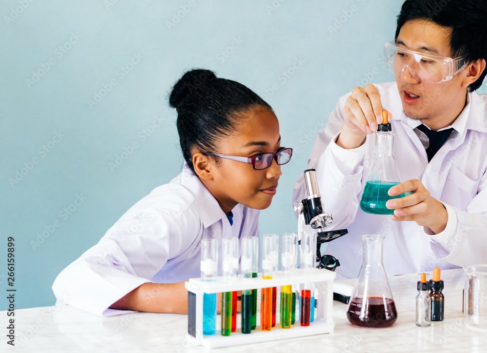 Close-up of male Asian science alchemist teacher teaching and doing chemistry laboratory test to curious African American elementary student Close-up of male Asian science alchemist teacher teaching and doing chemistry laboratory test to curious African American elementary student