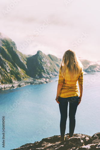 Woman traveling in Norway summer vacations tourist standing alone on mountain cliff over sea active lifestyle adventure trip outdoor