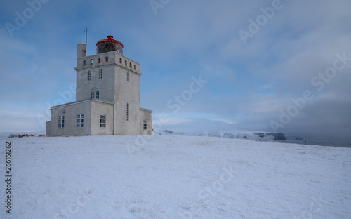 Panoramic image of the lighthouse of Cape Dyrholaey with snow and early morning light, winter in Iceland