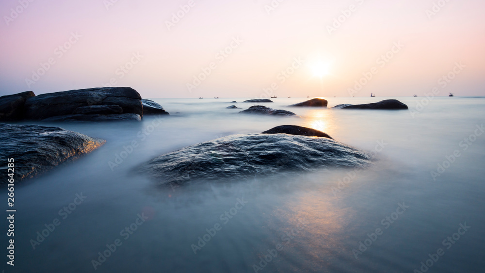 Sunrise on the beach, black rocks, beautiful light in the morning