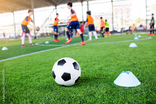 football between marker cones on green artificial turf with blurry soccer team training © Koonsiri