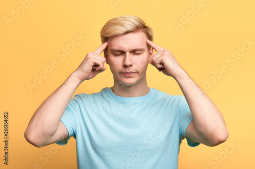 handsome man with closed eyes, suffering from severe headache,touching temples with fingers. close up photo. guy is concentrated on his thoughts, man tries to remember something