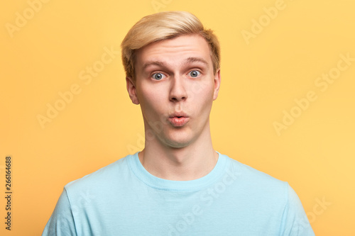 handsome man with funny facial expression learning to whistle., singing a song, flirting with a girl. close up photo. islated yellow background, emotion concept © the faces