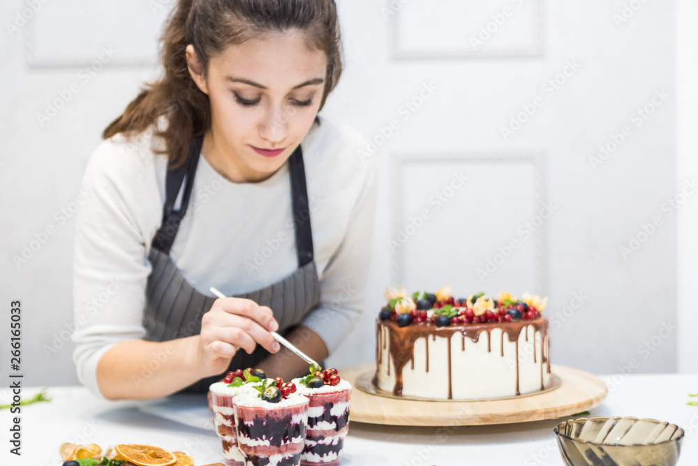 Decoration of the finished dessert. Pastry chef sprinkles confectionery with yellow powder. The concept of homemade pastry, cooking cakes.