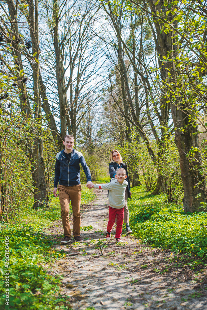 family of three walking by park trail in sunny day family of three walking by park trail in sunny day