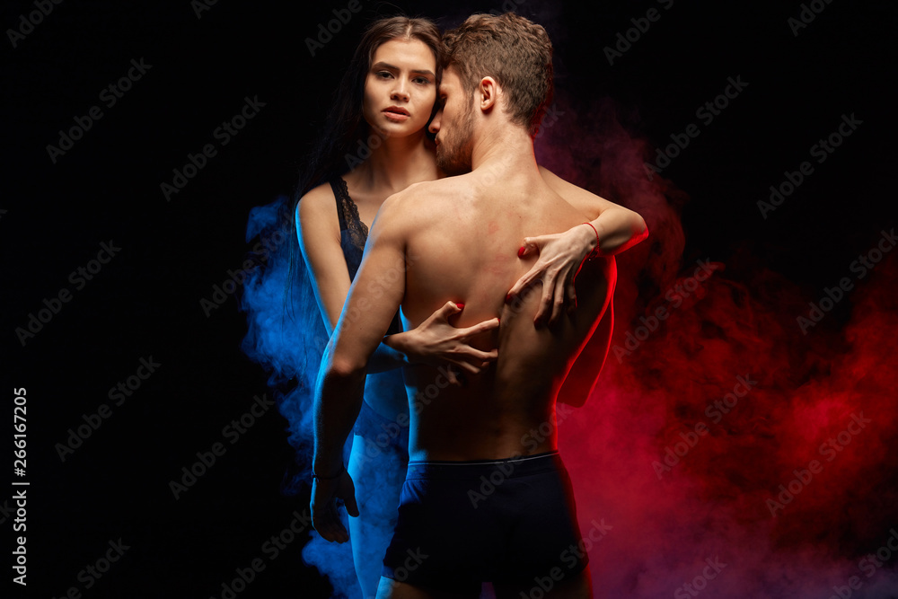 attractive girl holding her sexy lover in embrace, isolated black background.close up photo