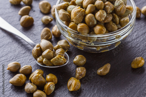 Fotografija pickled capers on a dark stone background