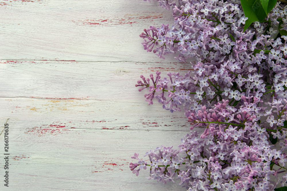 Fototapeta premium Frame of purple lilac and leaves on wooden background. Spring flowers. Decorative border, copy space, top view.