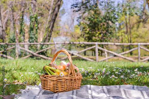 Basket with picnic food in the park. Green grass with flowers and lunch outdoors.
