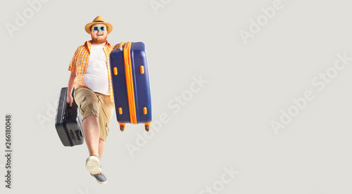 Obraz na plátne Fat funny man a suitcase smiling goes on a gray background.