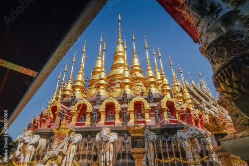 view a group of small golden pagoda Mandalay Style with blue sky background, Wat Phra That Suthon Mongkhon Khiri, famous attraction in Den Chai District, Phrae, northern of Thailand.