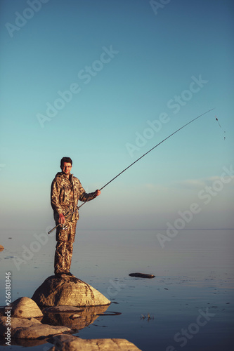 Man catches fish standing on stones in water