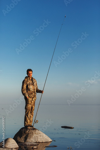 Man catches fish standing on stones in water