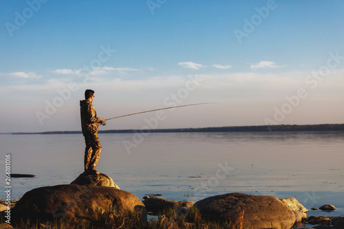 Man catches fish standing on stones in water