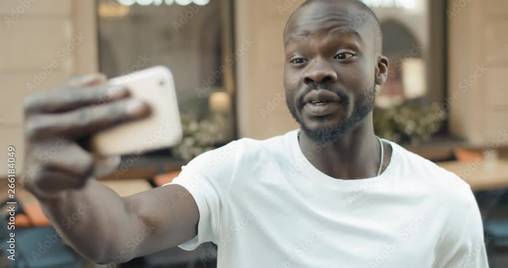 Excited laughing afro american man haveing videochat session using smartphone Excited laughing afro american man haveing videochat session using smartphone