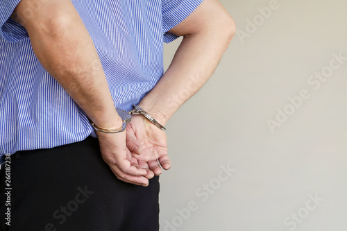 Close-up. Arrested elderly man handcuffed hands isolated on gray background. Prisoner or arrested terrorist, close-up of hands in handcuffs. Close-up view © polack
