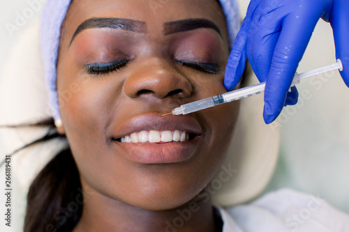 cropped shot of young african american woman getting beauty injection in lips isolated on white