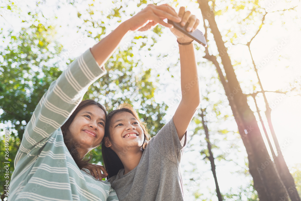 Asian mother and daughter feel relaxed taking a selfie in the park in the morning Asian mother and daughter feel relaxed taking a selfie in the park in the morning