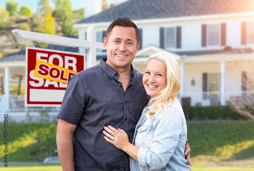 фотографія Happy Couple In Front of Sold Real Estate Sign and Beautiful House