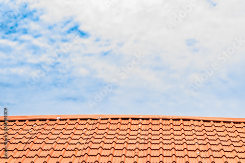 Red roof with a cloudy blue sky on top © Tola