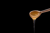 honey flows from the wooden spoon on a dark background