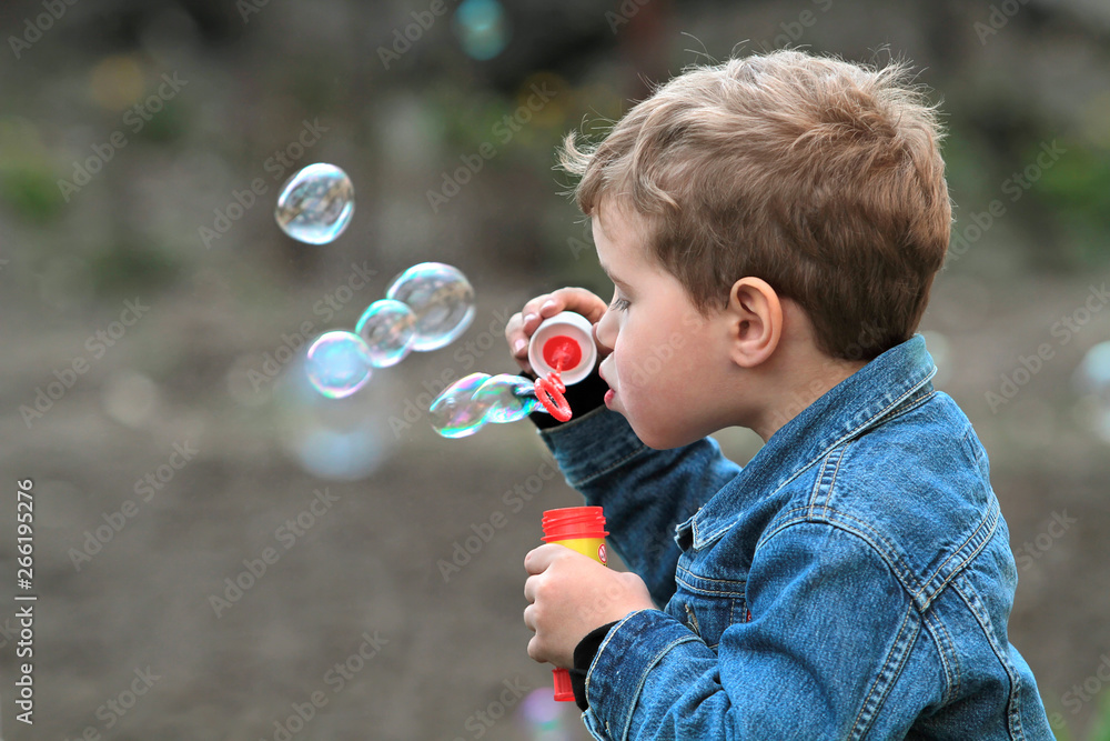The boy in the denim jacket blows bubbles The boy in the denim jacket blows bubbles