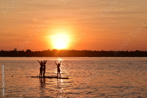 Silhouette of the young women doing yoga on sup board with paddle, Gili Trawangan Island, Indonesia © akturer