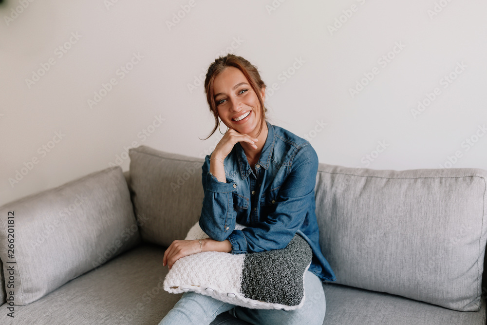 Smiling caucasian woman resting at home on cosy sofa at modern apartment wearing denim shirt and jeans Smiling caucasian woman resting at home on cosy sofa at modern apartment wearing denim shirt and jeans