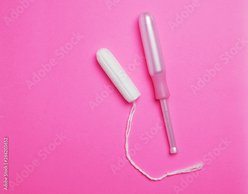 Woman Hygienic tampons with applicator on pink backdrop surface. photo