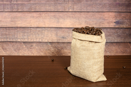 Coffee beans. Hard roasted coffee beans in jute burlack sack, on brown wooden table with rustic background.