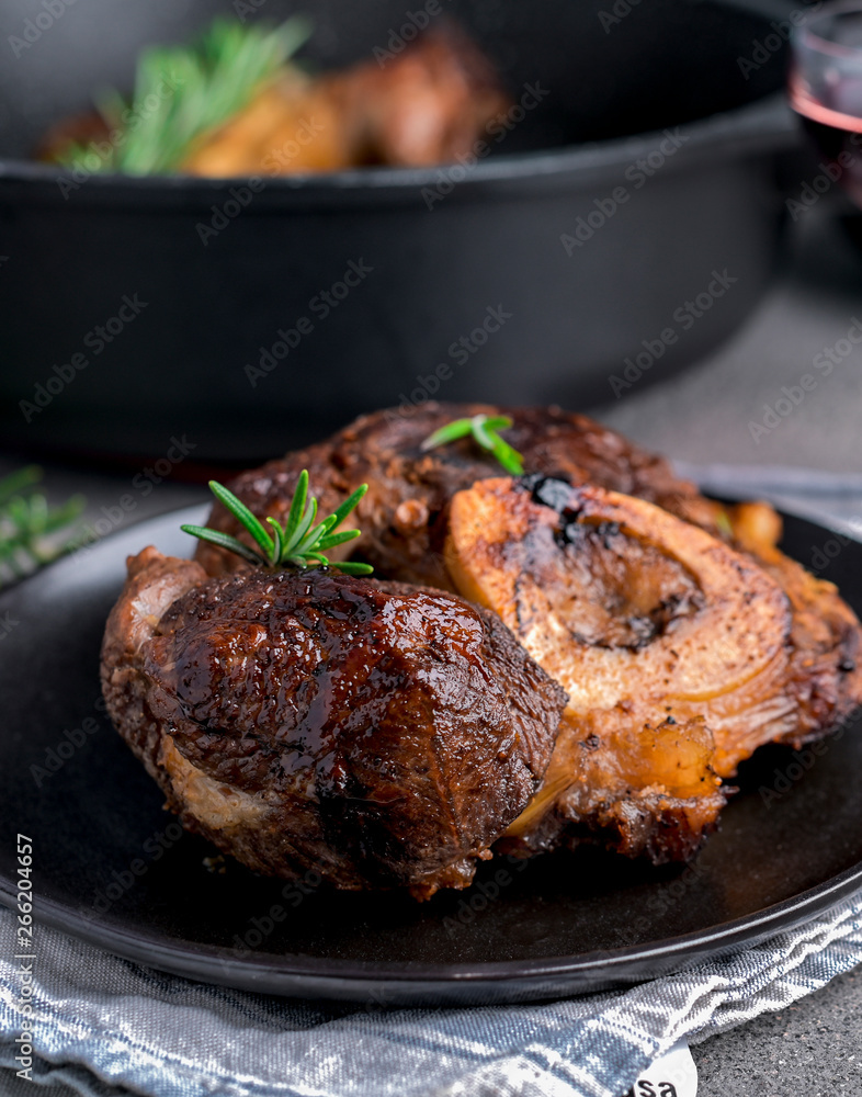 A large piece of fried meat on the bone in a plate and a glass of red wine. Served table for high-calorie lunch. A large piece of fried meat on the bone in a plate and a glass of red wine. Served table for high-calorie lunch.