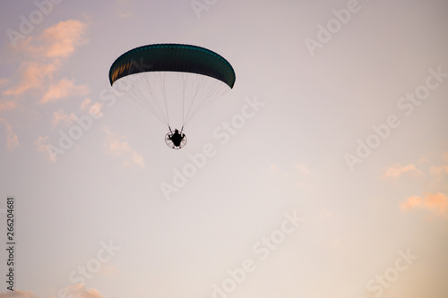 Paramotor silhouette flying on sky at sunset. Adventure, extreme sport and active life concept