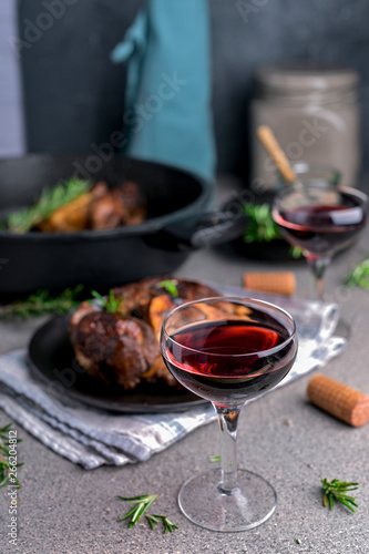 A large piece of fried meat on the bone in a plate and a glass of red wine. Hearty male lunch.