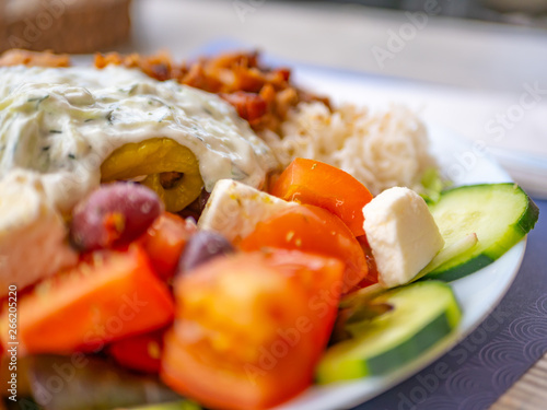 Close up of tomatoes, olives, feta cheese and slices of cucumbers from a famous Greek salad, against a blurred background