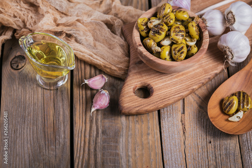 Fototapeta Naklejka Na Ścianę i Meble -  Grilled olives with garlic, olive oil and spices on wooden background