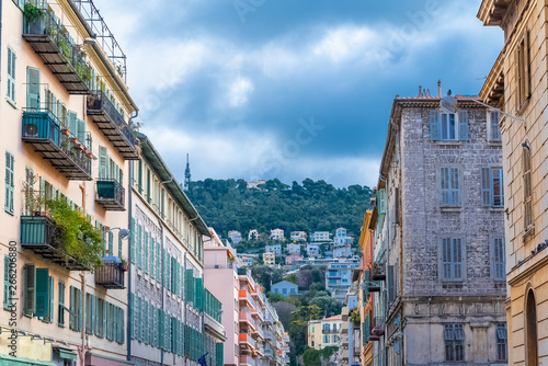 Nice, France, colorful facade, with typical windows and shutters, and the hills in background
