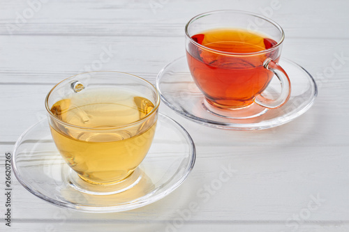 Two glass cups with different types of tea. Green and black tea in beautiful glass cups. Start your morning with right drink.