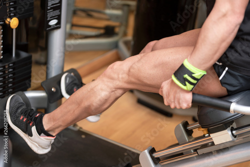 Handsome strong man performed leg press workout in the gym .