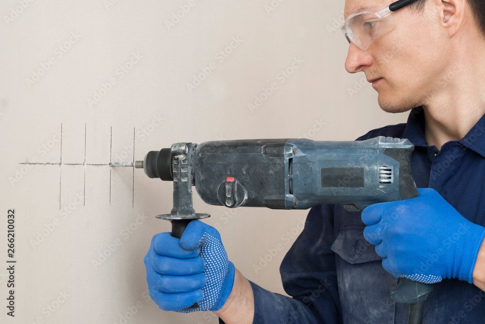 electrician worker drills a wall electrician worker drills a wall