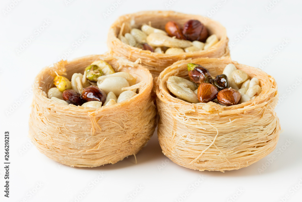 Traditional arabic dessert Kunafa with honey and nuts, on a white background, selective focus Traditional arabic dessert Kunafa with honey and nuts, on a white background, selective focus