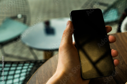 Hand holding a phone over the wooden table