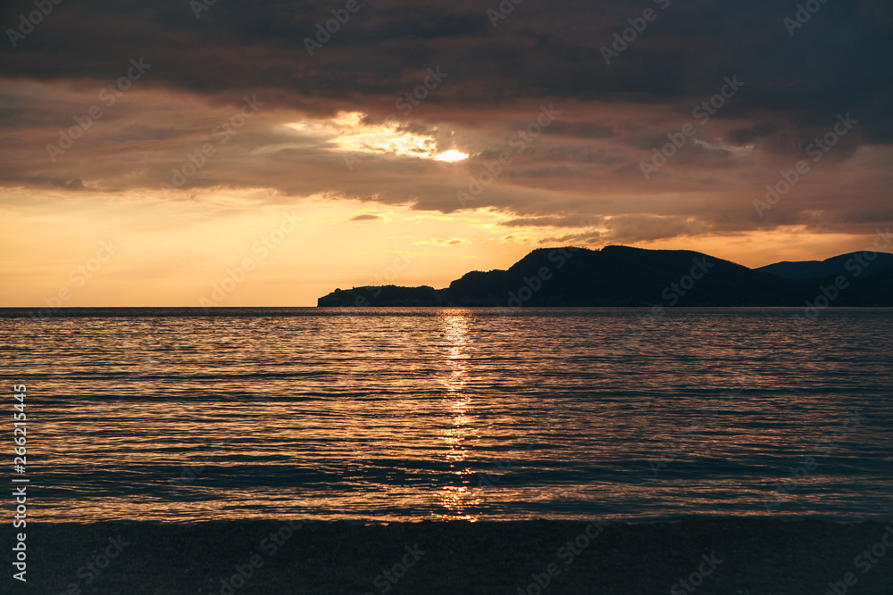 Beautiful view of the sunset or sunrise and the natural landscape with the sea and hills or mountains in Montenegro in the summer.