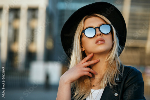 Outdoor fashion portrait of a glamorous blonde woman wearing hat and mirror sunglasses. Space for text