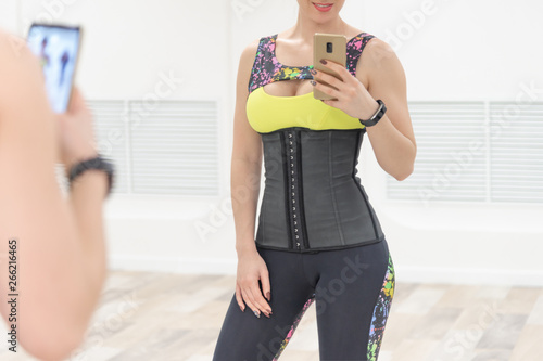 girl with a phone in a corset and sports leggings
