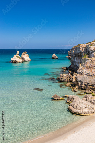 The bay of Torre dell'Orso, with its high cliffs, in Salento, Puglia, Italy. Turquoise sea and blue sky, sunny day in summer. A beach of fine white and pink sand. The stacks called the Two Sisters. photo