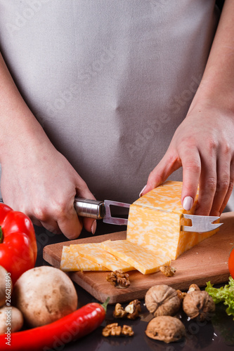 young woman slicing cheese in a gray apron