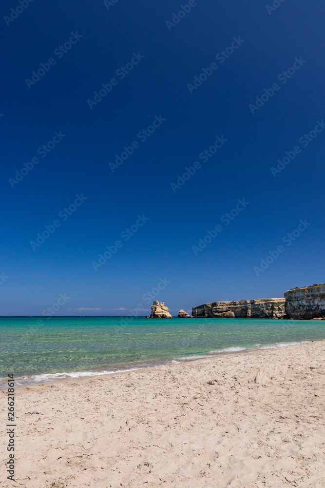 The bay of Torre dell'Orso, with its high cliffs, in Salento, Puglia, Italy. Turquoise sea and blue sky, sunny day in summer. Fine white sand beach. The stacks called the Two Sisters.