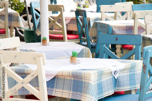 Tables and chairs in a typical traditional  Medierranean restaurant on terrace in light blue and white color photo