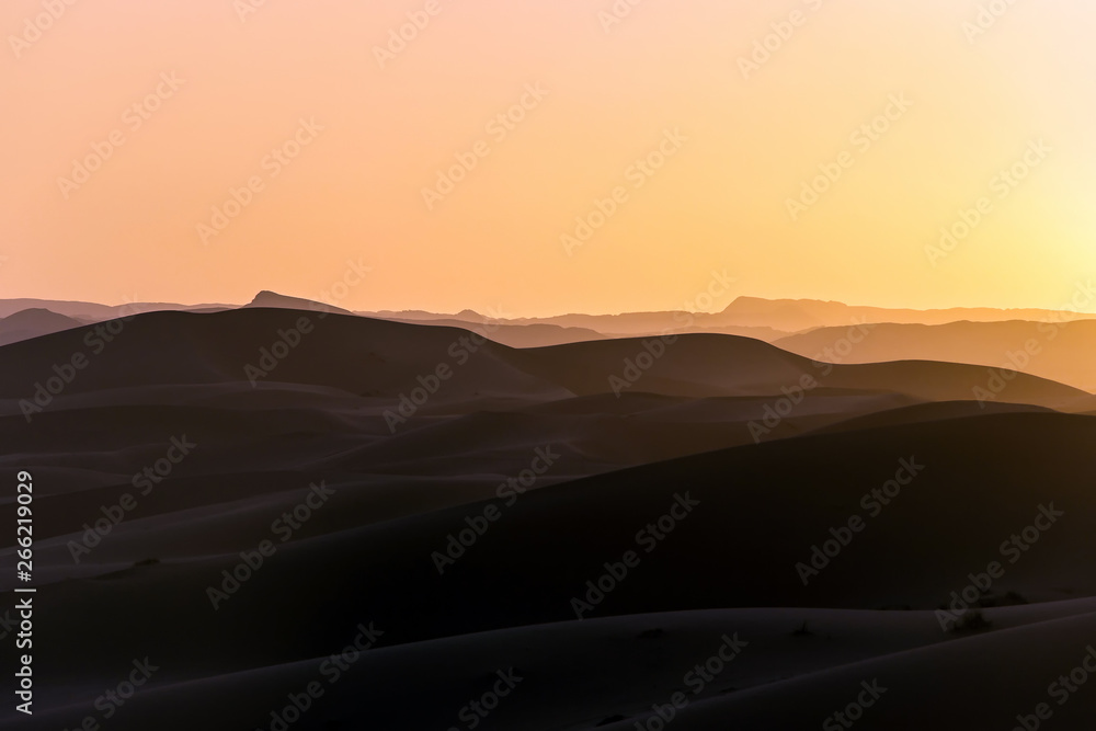 landscape of sand dunes in Sahara desert with fog at sunset