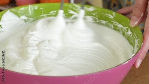 Kitchen mixer whips cream custard pastry whisk rotates rapidly. Food processor beat the eggs white egg whites into a thick foam. Kitchen machine in operation.